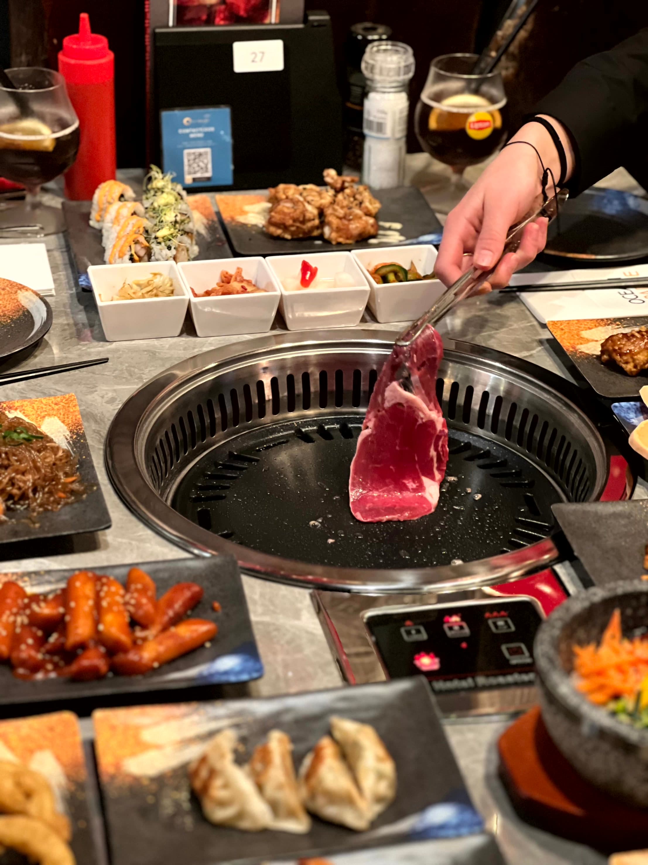 Vlees op de tafelgrill bij Korean BBQ Ocean Paradise, geserveerd met Koreaanse bijgerechten